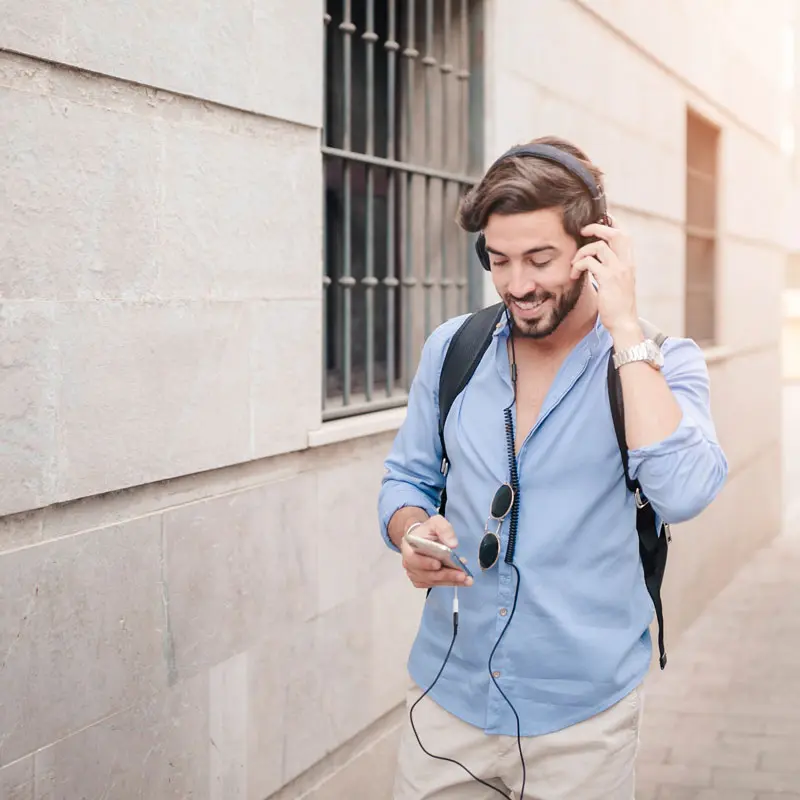 happy man walking pavement listening music